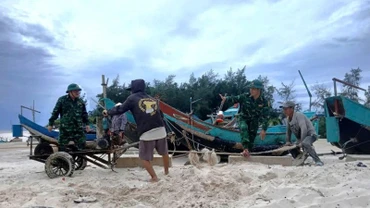 Cán bộ, chiến sĩ Đồn Biên phòng Roòn (Quảng Trị) giúp dân kéo, chuyển thuyền đánh cá lên bờ.