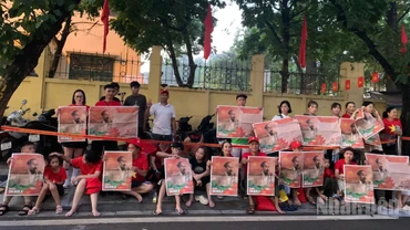 Người dân giơ cao tờ phụ san Báo Nhân Dân in ảnh Bác Hồ chào đón đoàn xe diễu binh trên đường Cửa Bắc.