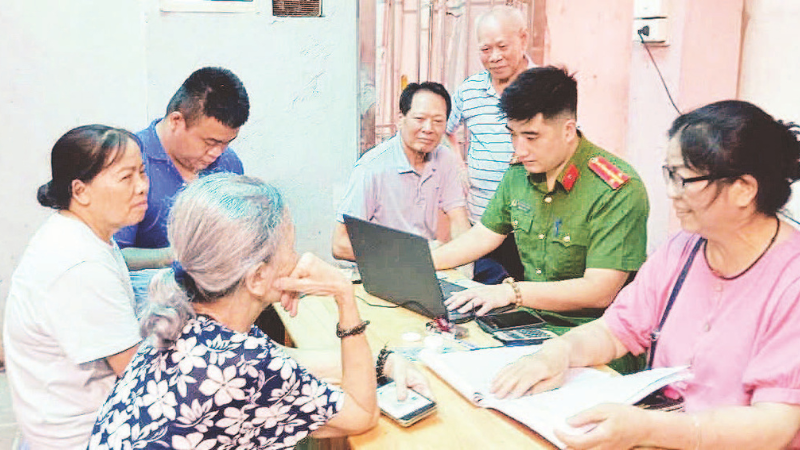 Công an phường Tây Hồ hướng dẫn cán bộ, đảng viên cài đặt ứng dụng thực hiện thủ tục hành chính đảng. (Ảnh QUANG THÁI)