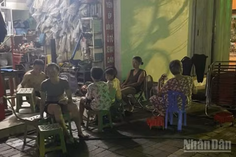 Người dân trên phố Hai Bà Trưng (phường Thái Bình, tỉnh Hưng Yên) dùng đèn ắc quy ngồi chờ trong lúc bị ngừng cấp điện.