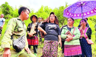 Trưởng bản Mùa A Thi (ngoài cùng, bên trái) trao đổi với người dân trong bản. (Ảnh VŨ LỢI)