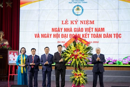 Đồng chí Đỗ Văn Chiến tặng hoa, chúc mừng các thầy giáo, cô giáo và toàn thể sinh viên Học viện Tài chính. (Ảnh: SƠN TÙNG)