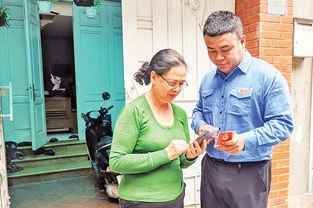 Đoàn viên thanh niên phường Thụy Khuê (Tây Hồ) hướng dẫn sử dụng ứng dụng “Sổ tay đảng viên điện tử Thành ủy Hà Nội”. (Ảnh VIẾT TUẤN)