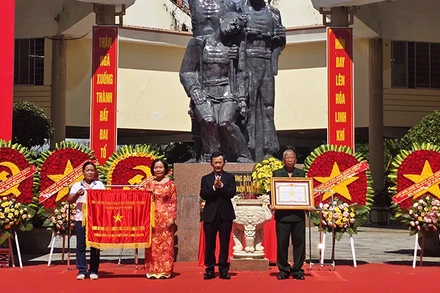 Đồng chí Dương Văn Trang trao tặng cờ và danh hiệu Anh hùng Lực lượng vũ trang nhân dân cho đại diện Tập thể chiến sĩ cách mạng bị địch bắt tù đày tại Ngục Kon Tum. 