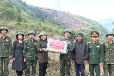 Đồng chí Phạm Thị Tuyên, Phó Chủ tịch Ủy ban nhân dân huyện Tuần Giáo tặng quà, động viên cán bộ, chiến sĩ Trung đoàn 82 đang thực hiện nhiệm vụ giúp người nghèo ở huyện Tuần Giáo đào hố trồng cây mắc-ca.