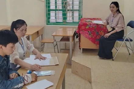 Thí sinh Thào A Dũng được hai giám thị hỗ trợ làm bài thi vào lớp 10 tại Hội đồng thi trường trung học cơ sở-trung học phổ thông Quyết Tiến (huyện Tủa Chùa). 