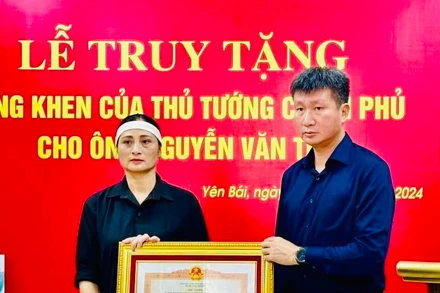 Chủ tịch Ủy ban nhân dân tỉnh Yên Bái Trần Huy Tuấn trao Bằng khen của Thủ tướng Chính phủ cho gia đình anh Nguyễn Văn Thi. (Ảnh: THANH SƠN)