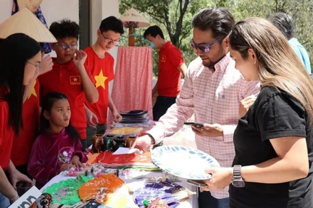 Khách hàng tham quan gian trưng bày các sản phẩm thủ công mỹ nghệ tại sự kiện. (Ảnh: TTXVN)