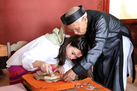 Bazhan Adina, diễn viên phim "Zere", đến từ Kazastan được nghệ nhân Nguyễn Đăng Chế hướng dẫn in tranh. (Ảnh: KHIẾU MINH)