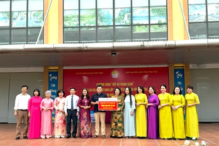 Đại diện Câu lạc bộ Di sản áo dài Việt Nam trao biểu trưng 206 bộ áo dài cho Trường Phổ thông trung học huyện Tân Sơn. (Ảnh: Ban tổ chức)