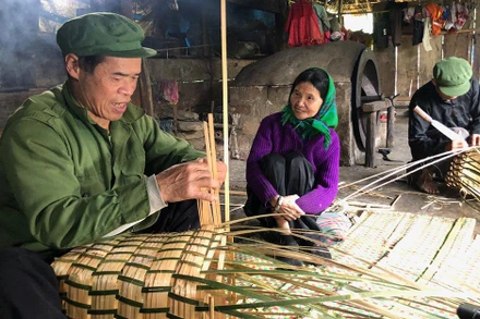 Ông Lâm A Liên và ông Lâm A Diện đang đan gùi trong căn bếp nhà mình.