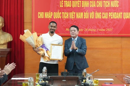 Đại diện Sở Tư pháp thành phố Hà Nội trao quyết định nhập quốc tịch Việt Nam cho cầu thủ Cao Pendant Quang Vinh. (Ảnh: PHAN THẠCH)