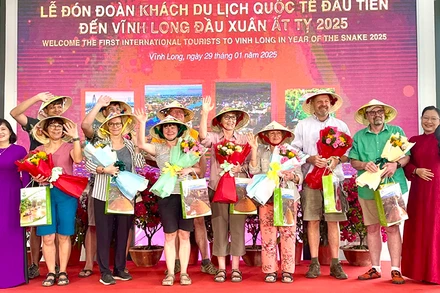 Lãnh đạo tỉnh Vĩnh Long tặng quà và hoa cho khách du lịch quốc tế đầu tiên. 