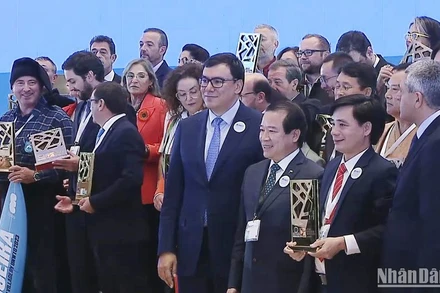 Chủ tịch UBND xã Tân Hóa nhận Giải thưởng “Làng du lịch tốt nhất” của UNWTO với sự chúc mừng của Phó Cục trưởng Hà Văn Siêu và Tổng Thư ký UNWTO Zurab Pololikashvili. (Ảnh chụp từ clip của UNWTO) 