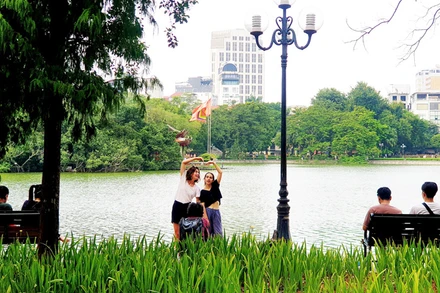 Du khách nước ngoài chụp ảnh tại Hồ Gươm, Hà Nội (Ảnh: T.LINH)