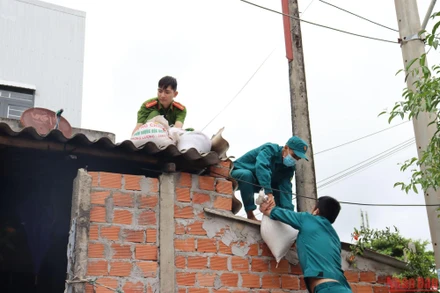 Lực lượng chức năng giúp người dân thị xã Đức Phổ (Quảng Ngãi) chằng chống nhà cửa.