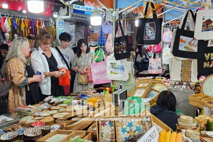 Du khách nước ngoài thích thú mua đồ lưu niệm đậm chất Việt Nam tại chợ đêm phố cổ, Hà Nội, tháng 1/2024. (Ảnh: T.LINH)