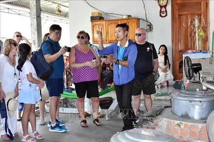 Các du khách Tàu Spectrum of the Seas hào hứng, thích thú khi tham quan nghề nấu rượu truyền thống tại TP Bà Rịa, tỉnh Bà Rịa-Vũng Tàu ngày 26/2. (Ảnh: TTXVN)