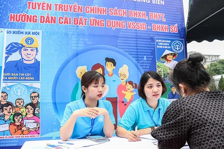 Cán bộ Bảo hiểm xã hội quận Long Biên, Hà Nội giới thiệu chính sách với người lao động. (Ảnh: NGÂN ANH)