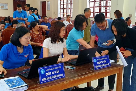 Cán bộ bảo hiểm xã hội hướng dẫn người dân cài đặt VssID. (Ảnh: Tâm Trung)