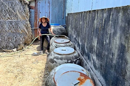 Bà Lý Thị Xuyên bơm nước dưới ao chứa vào lu, xử lý lại bằng phèn chua để có nước tắm, giặt.