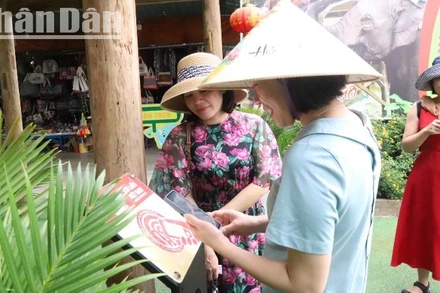 Du khách phấn khởi khi trải nghiệm tìm hiểu về Trung tâm Du lịch Cầu treo Buôn Đôn qua bảng gắn chip NFC (công nghệ kết nối không dây) thuộc Dự án “Yêu lắm Việt Nam” do Báo Nhân Dân phối hợp các đối tác công nghệ triển khai thực hiện.