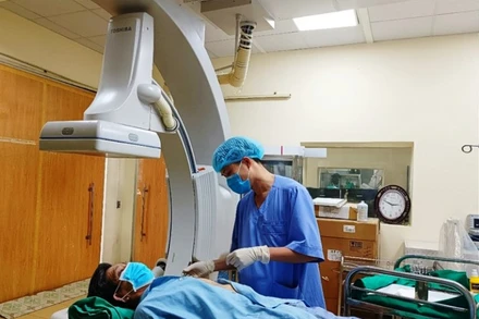 Nhân viên y tế sử dụng thiết bị hiện đại kiểm tra sức khỏe bệnh nhân sau can thiệp tim mạch.