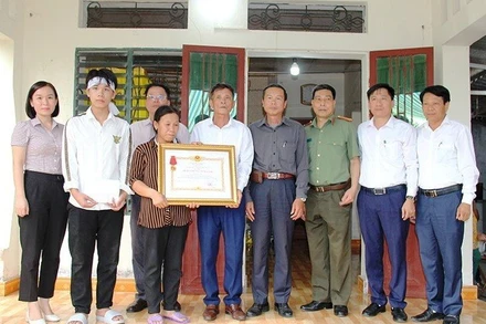 Đại diện đoàn công tác trao Huân chương Dũng cảm cho người thân anh Phạm Ngọc Anh.