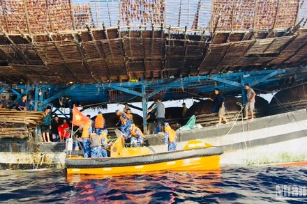 Lực lượng cứu nạn tàu Cảnh sát biển 8002 tiếp cận ngư dân tàu QNa 90129 trên tàu câu mực để chăm sóc y tế.