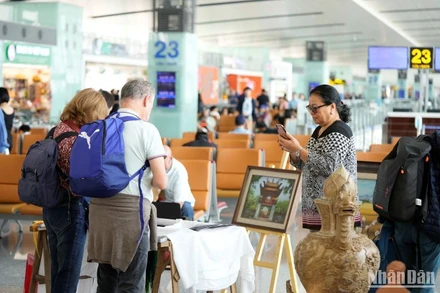 Hành khách nước ngoài chăm chú chiêm ngưỡng các bức tranh thêu thủ công tại Nhà ga T2 Nội Bài.