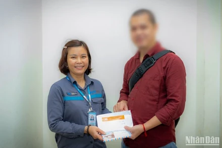 Chị Tươi trao lại chiếc túi chứa 4.300 USD cho anh V.Q.Đ. trong niềm vui sướng của anh.