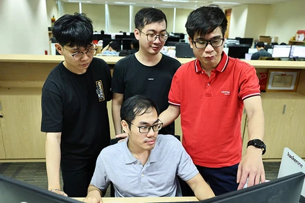 Nguyễn Tuấn Anh (áo đỏ) trao đổi nghiệp vụ với đồng nghiệp tại nhiệm sở. 