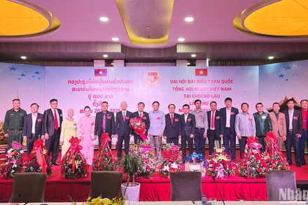 Đại sứ Nguyễn Bá Hùng tặng hoa chúc mừng Chủ tịch và Ban Chấp hành khóa III Tổng hội người Việt Nam tại Lào. (Ảnh: Trịnh Dũng)