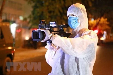 Phóng viên Truyền hình Thông tấn tác nghiệp trong thời gian cao điểm chống dịch bệnh Covid-19. (Ảnh: Quốc Dũng/TTXVN)