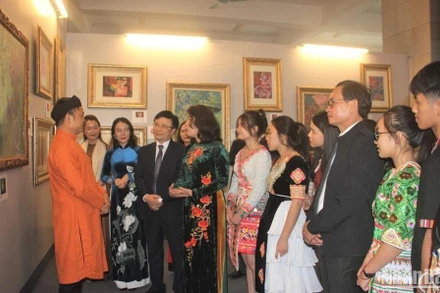 Họa sĩ Nguyễn Tuấn Sơn (ngoài cùng bên trái) giới thiệu tranh về thơ Hồ Xuân Hương tới lãnh đạo tỉnh và người dân. (Ảnh: Minh Quân)