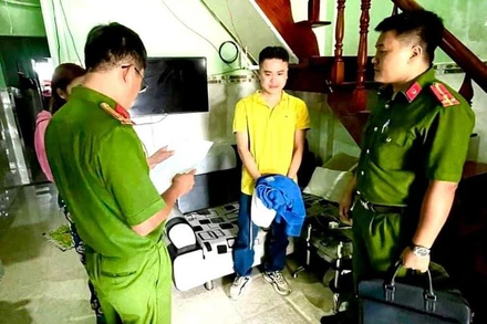 Cơ quan Cảnh sát điều tra Công an Bình Thuận đọc Quyết định khởi tố bị can, bắt tạm giam Nguyễn Quốc Đạt (đứng giữa, áo vàng). (Ảnh: Công an cung cấp)