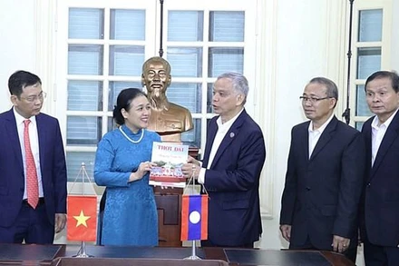 Bà Nguyễn Phương Nga tặng Chủ tịch Ủy ban Hòa bình và Đoàn kết Lào Sommad Pholsena cuốn đặc san "60 năm hữu nghị Việt Nam-Lào: Chung dãy Trường Sơn" của Tạp chí Thời Đại. (Nguồn: Báo Hà Nội mới)