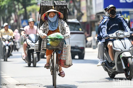 Dưới ánh nắng gay gắt, kèm nhiệt độ cao, nhiều người lao động ở Hà Nội phải trùm kín người khi di chuyển ngoài trời. Ảnh: THÀNH ĐẠT