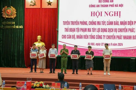 Phó Giám đốc Công an thành phố Hà Nội Nguyễn Thanh Tùng trao ấn phẩm tuyên truyền phòng chống ma túy cho đại diện các công ty chuyển phát nhanh bưu điện EMS.