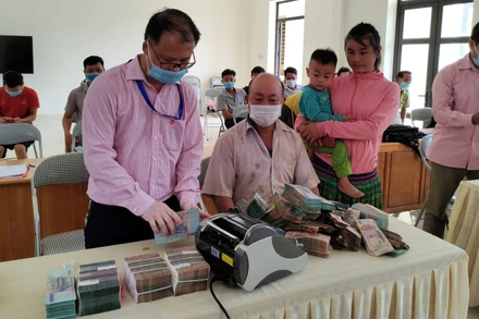 Cán bộ Ngân hàng Chính sách xã hội giúp bà con xếp gọn tiền trước khi gửi tiết kiệm tại Điểm giao dịch.