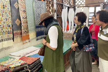 Du khách tham quan gian hàng bày bán vải thủ công của Lào. (Ảnh: Hải Tiến)