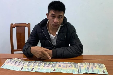 Đối tượng Đoàn Văn Dương với số tiền giả mà cơ quan chức năng thu giữ. (Ảnh: Công an cung cấp)