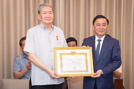 Đồng chí Trần Cẩm Tú trao Quyết định tặng Huy hiệu 50 tuổi Đảng cho đồng chí Đinh Thế Huynh. (Ảnh: SƠN TÙNG)