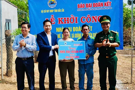 Nhà báo Trương Thành Trung, Tổng Biên tập Báo Đại Đoàn Kết cùng Đại tá Rơ Lan Ngân, Phó Chính ủy, Bộ đội Biên phòng tỉnh Đắk Lắk; lãnh đạo xã Krông Na trao bảng tượng trưng cho gia đình ông Y Hớn Niê. (Ảnh: THANH NGA)