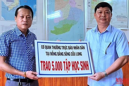 Chủ tịch Ủy ban nhân dân huyện Đầm Dơi (bìa phải) tiếp nhận 5.000 tập hỗ trợ từ Cơ quan Thường trực Báo Nhân Dân tại vùng đồng bằng sông Cửu Long.