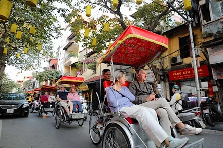 Du khách nước ngoài sử dụng xích-lô thưởng ngoạn nét đẹp cổ kính của Phố cổ Hà Nội. (Ảnh: TTXVN)