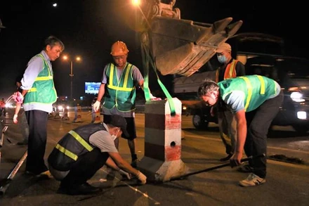 Đơn vị thi công dịch chuyển dải phân cách để bố trí làn riêng cho xe máy trên cầu Thanh Trì.