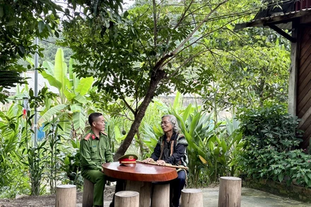 Trung tá Ating Chơn trao đổi với già làng Bríu Pố về công tác giữ gìn an ninh trật tự.