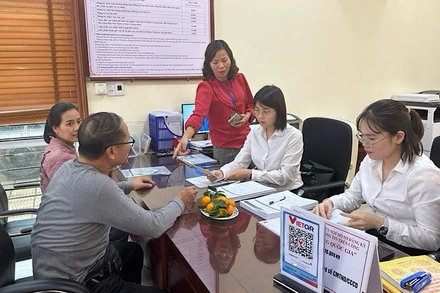 Cán bộ ngân hàng hướng dẫn người dân mở tài khoản để thực hiện chi trả an sinh xã hội không dùng tiền mặt. 