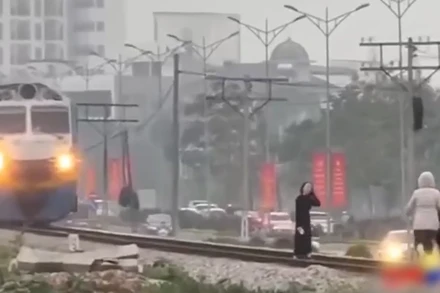 Đoàn tàu đang lao tới, nhưng người phụ nữ vẫn thản nhiên tạo dáng trên đường ray như thể đang chụp ảnh nghệ thuật. (Ảnh cắt từ clip)